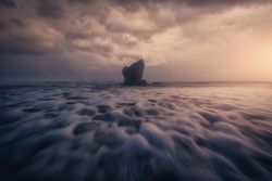 Coastal rock on beach and overcast sky