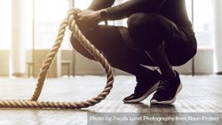 Close up of a man sitting on his toes holding a pair of battle ropes for workout 4mqOX4