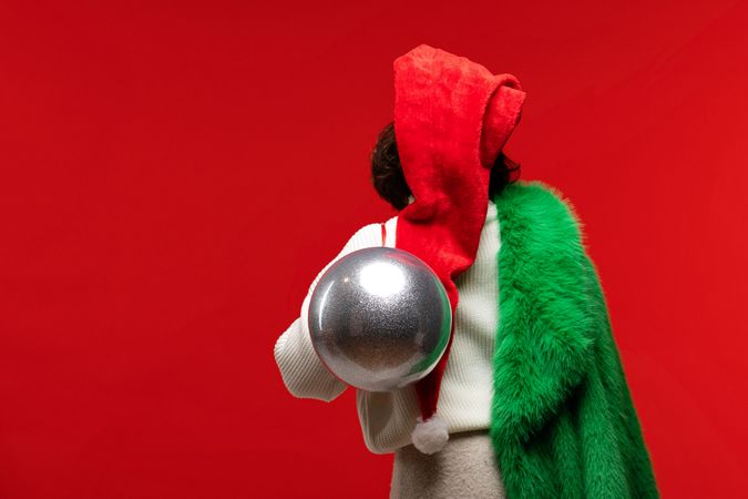 Back view of woman in festive outfit carrying silver ornament.