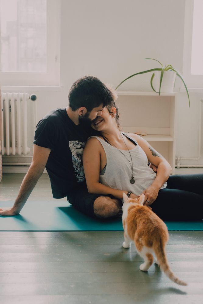 Loving couple cuddling on floor while cat walking around