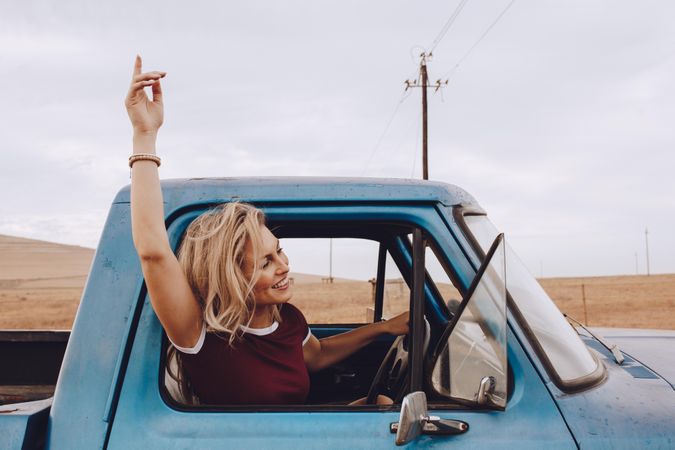 Beautiful young woman driving a car and enjoying road trip