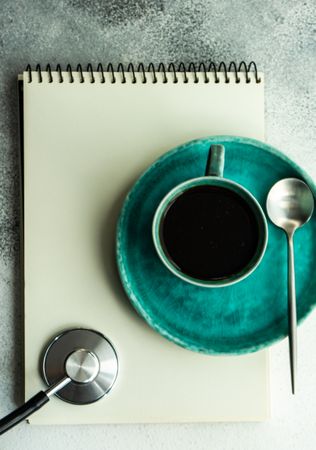 Top view of coffee cup with stethoscope and notepad
