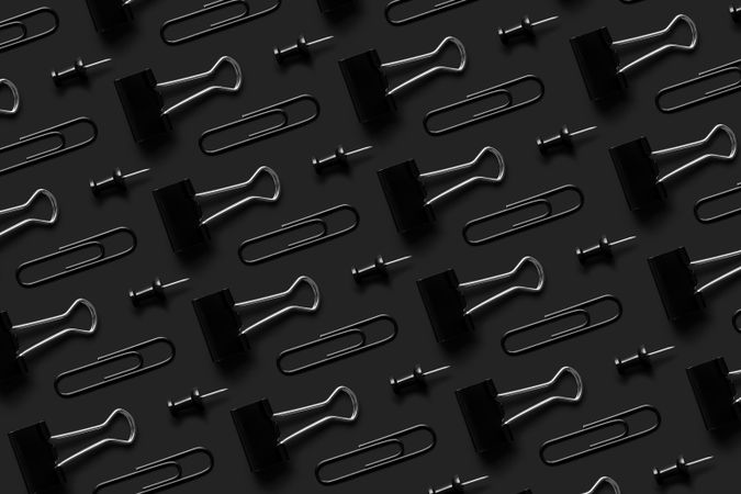 Binder clips and tacks on a dark background