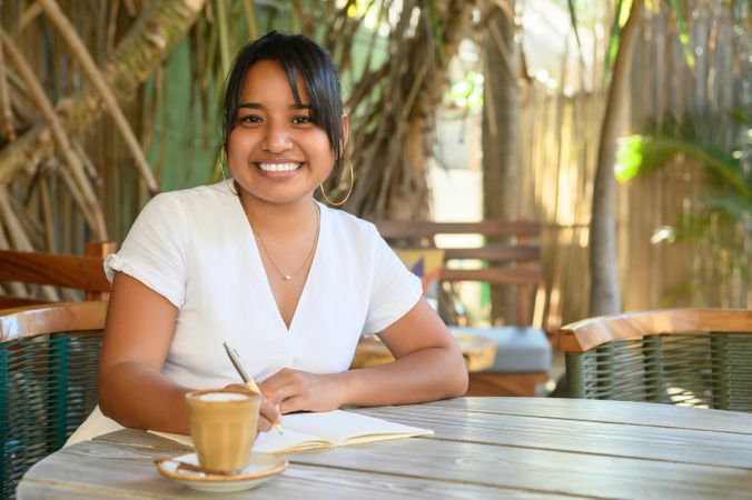 Happy woman taking notes in outdoor cafe