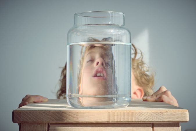 Sleepy boy reflection in glass bottle with water