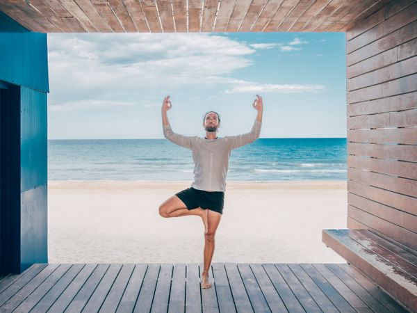Man doing yoga by the beach