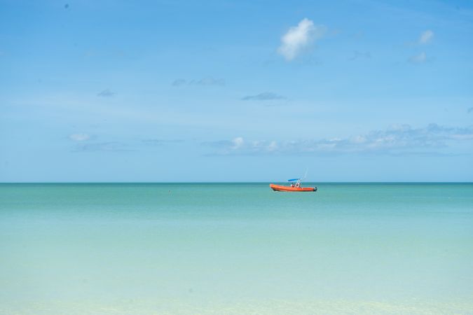 Orange boat in sea under blue sky