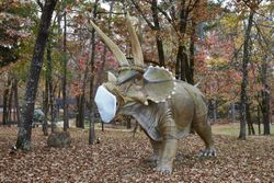 A menacing Triceratops dinosaur figure in a protective mask, AR 4BJWB4