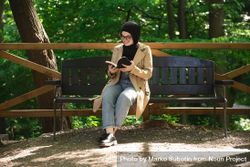 Middle Eastern woman engaged in a book while sitting on a park bench 4ZBMr4