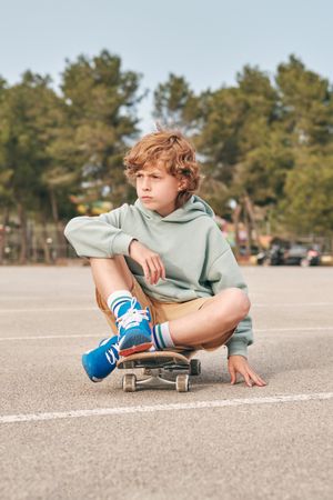 Teen boy sitting on skateboard in city