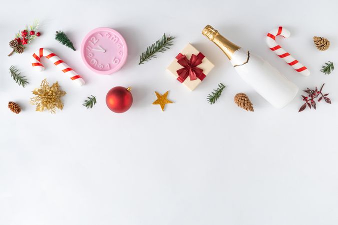 Holiday decorations; present, candy cane and pine cone arranged at top border of light background