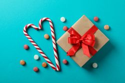 Sweet candy canes and gift box on turquoise background, space for text