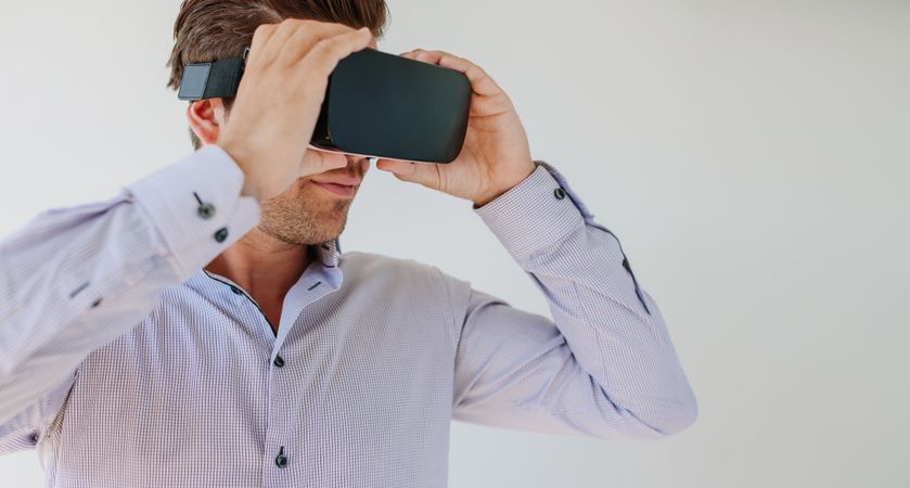Close up shot of young man wearing virtual reality goggle against grey background