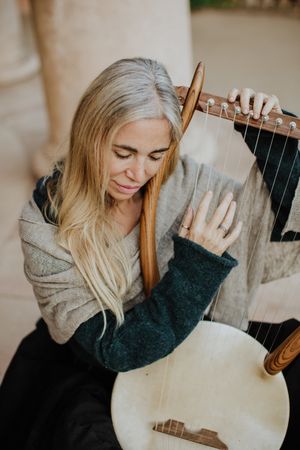 Romantic female musician playing lyre in terrace