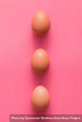 Row of three brown Easter eggs on pink background 42Jmg4