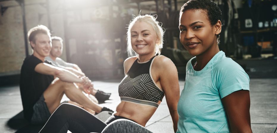 Multi-ethnic group of people sitting on gym floor after work out