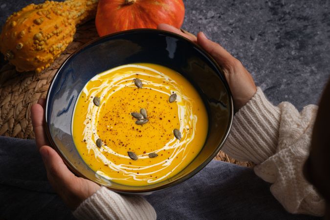 Crop woman with bowl of pumpkin soup