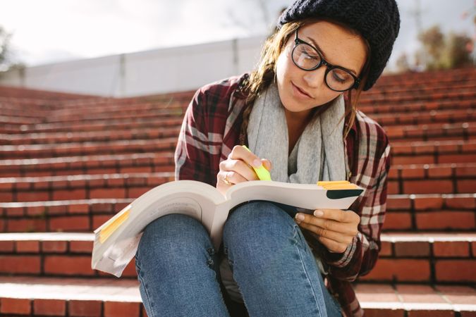 Young woman marking book with highlighter pen