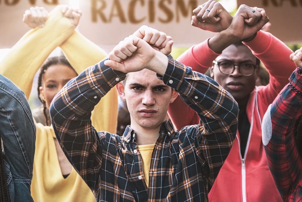 A group of young people participates in a march, with crossed arms above their head