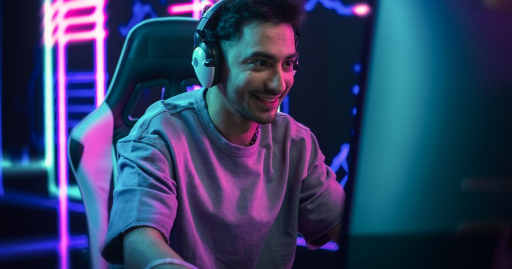 Portrait of a Happy Young Man in Headphones Talking with Friends Online on a Computer.