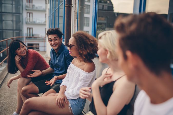 Multiracial group of friends sitting on balcony in city