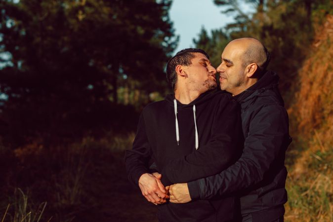 Smiling men hugging on path in park