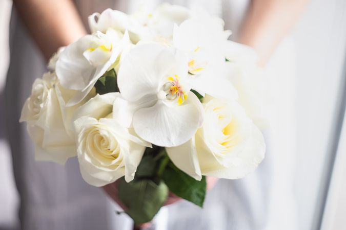 Female holding wedding bouquet with roses and orchids