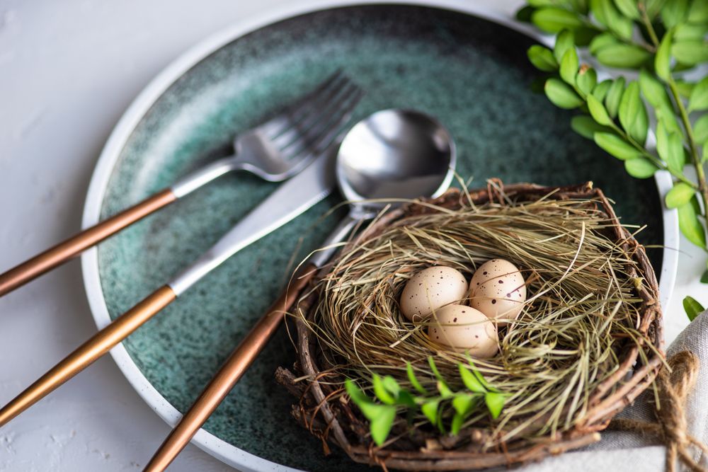 Easter table setting with nest and mini eggs, on blue plate with silverware
