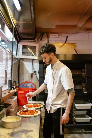 Pizza man making pizza in the kitchen of a pizzeria