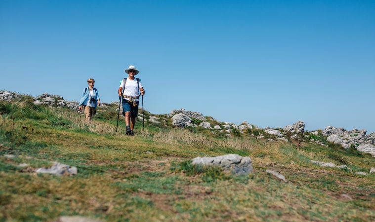 Three adults hiking on hill with poles