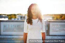 Serious Black woman standing on roof backlit with sun 4jZ7r4