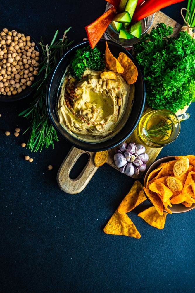 Top view of traditional hummus spread with veggies and chips to dip