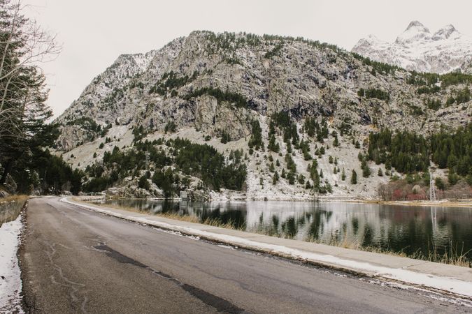 Countryside road between snow hills and lake