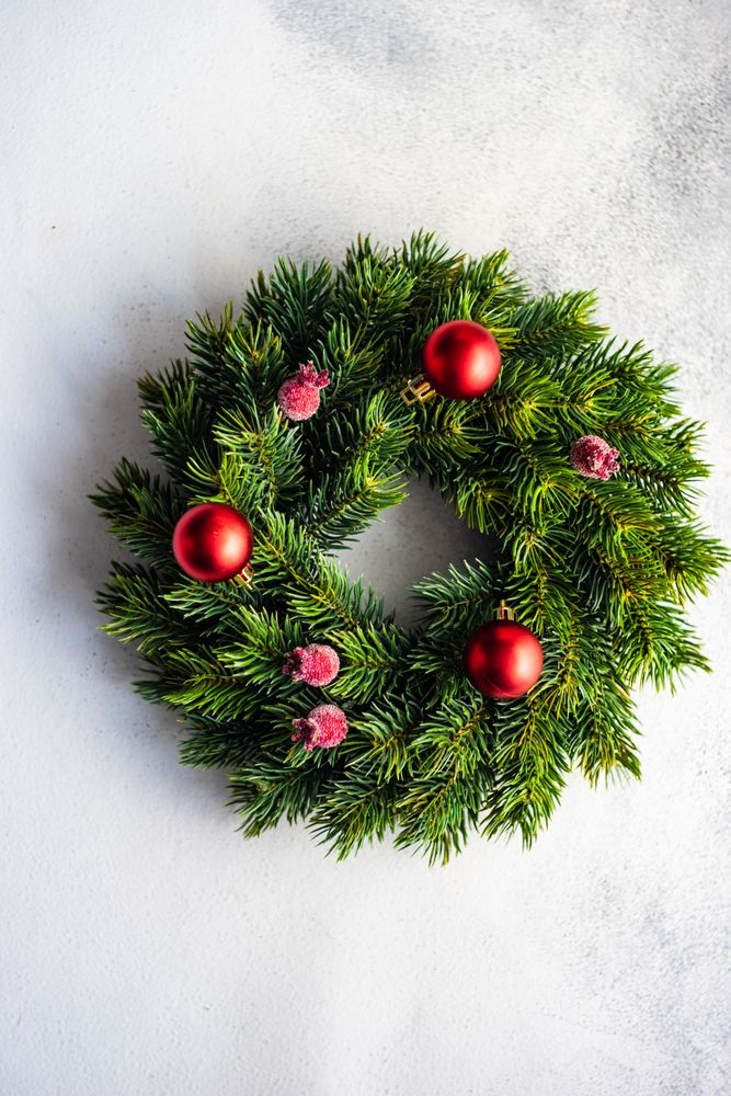 Holiday wreath with red baubles and berries on marble counter