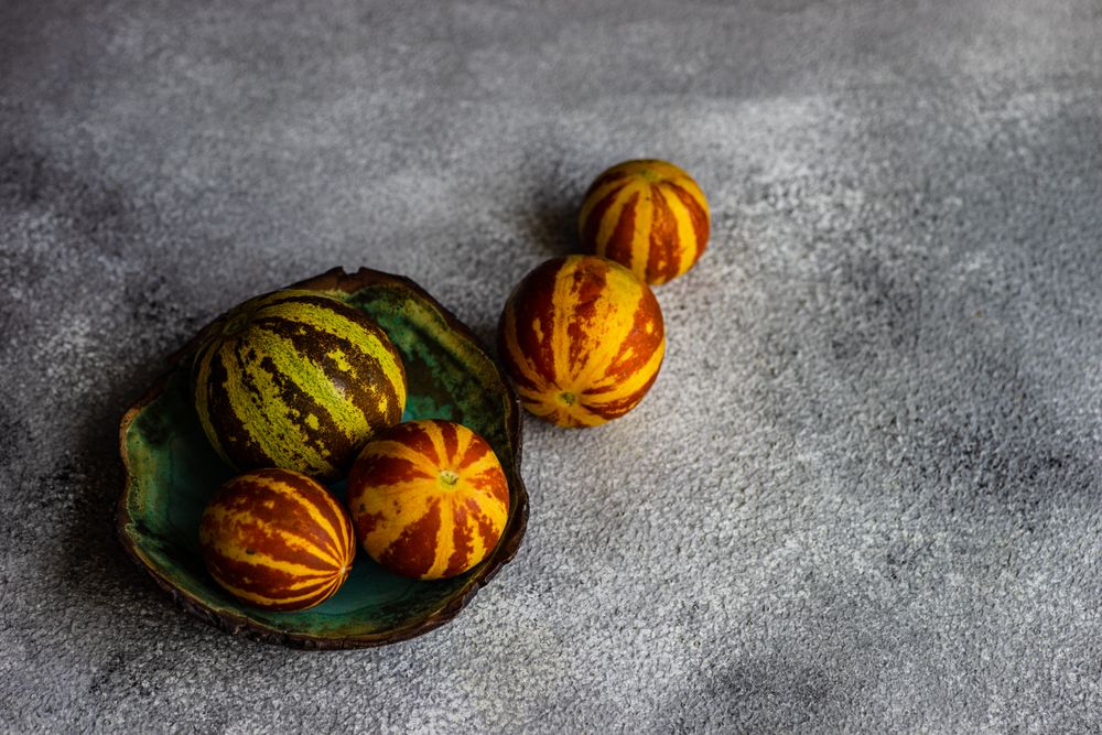 Organic mini melons on grey counter with space for text