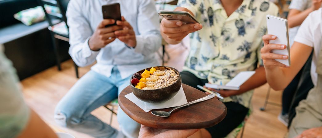 Unrecognizable chef showing exotic dish to food bloggers taking pictures during cooking master class