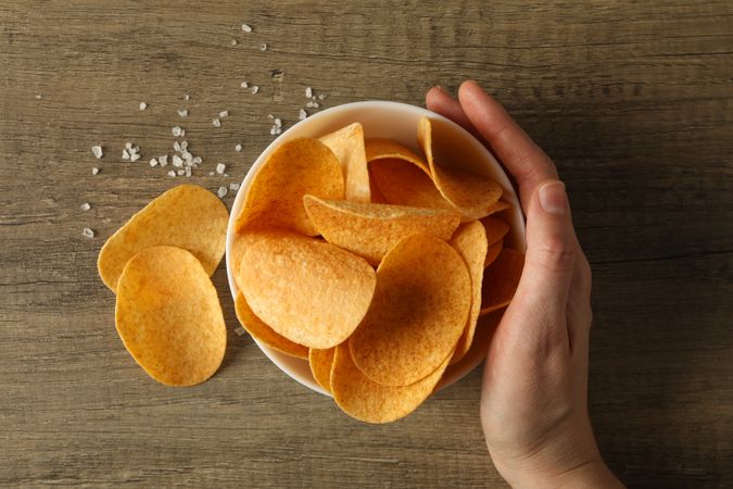 Potato chips in a bowl on a wooden background