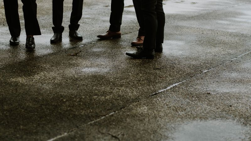 Cropped image of men in formal shoes standing on asphalt road