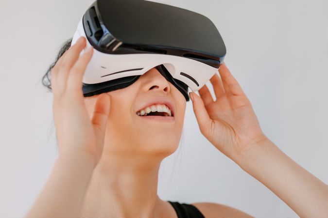 Close up shot of happy young woman using the VR goggles against grey background