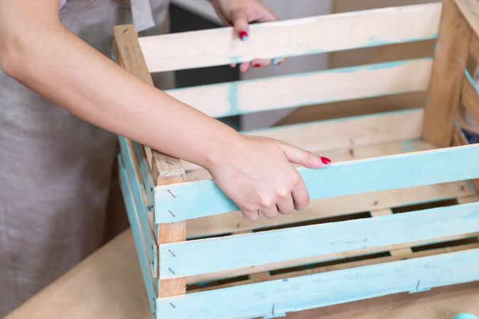Woman paining wooden box in blue color