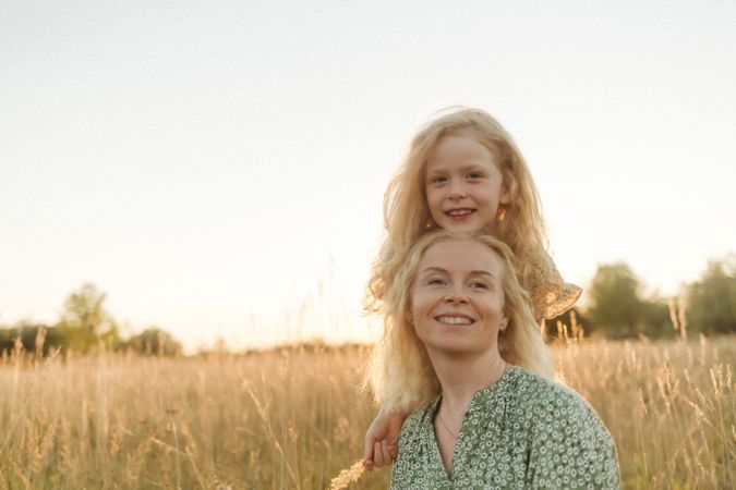 Happy mother and little daughter in field during summer