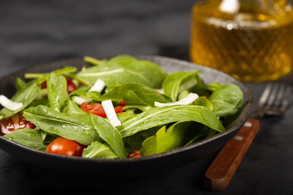 Arugula salad with tomatoes on dark background.
