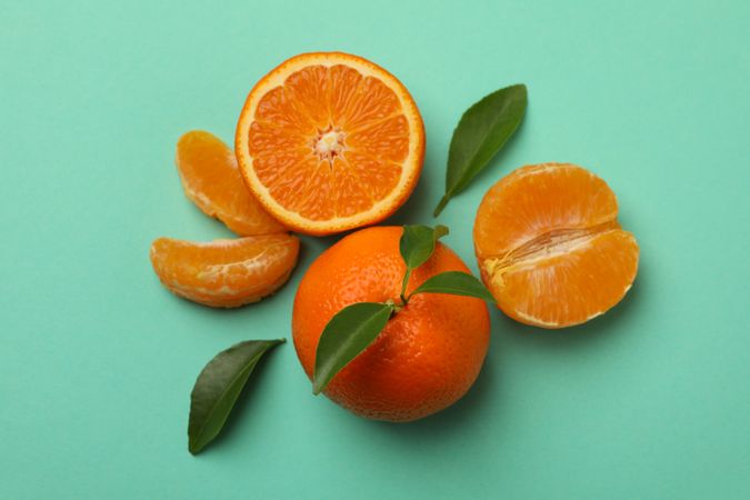 Ripe mandarins with leaves on mint background, top view