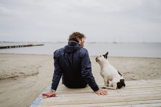Man and dog resting on beach together