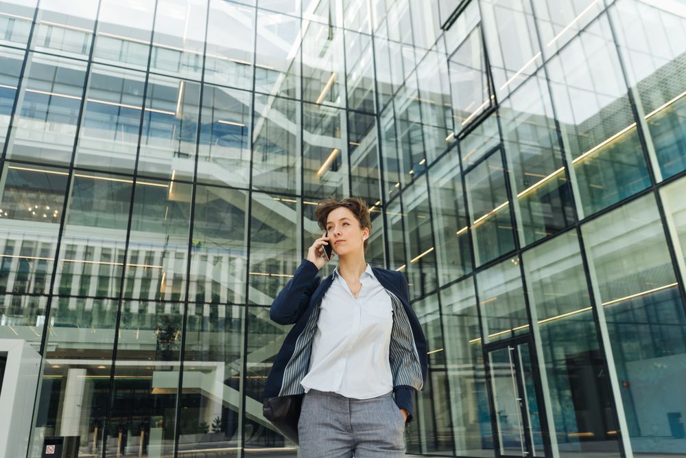 Smiling entrepreneur browsing smartphone outside office building