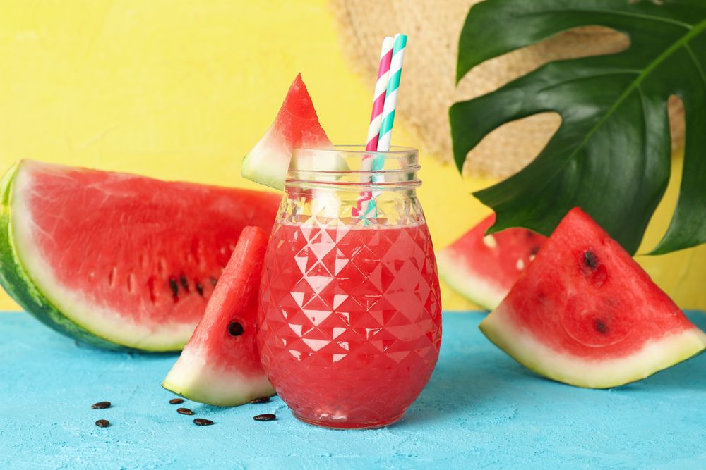 Composition with watermelon juice on blue table. Summer fruit