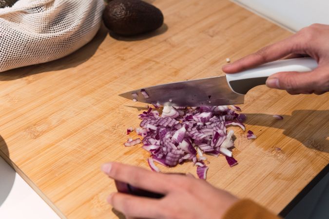 Crop woman cutting onion in kitchen