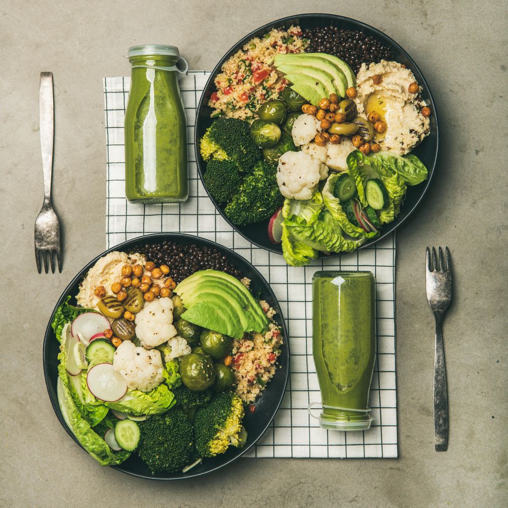 Two vegetarian bowls, with smoothie, on placemat, square crop