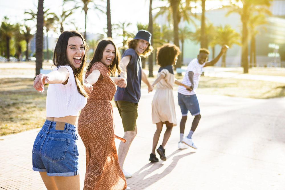 Multiethnic group of young friends running happily together while holding hands