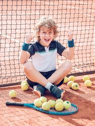 Excited kid celebrating successful tennis match on court